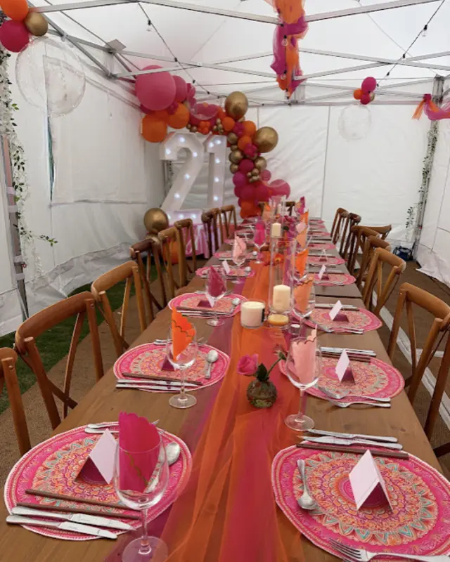 A 21st birthday table in pink and orange with balloon arch and light-up numbers