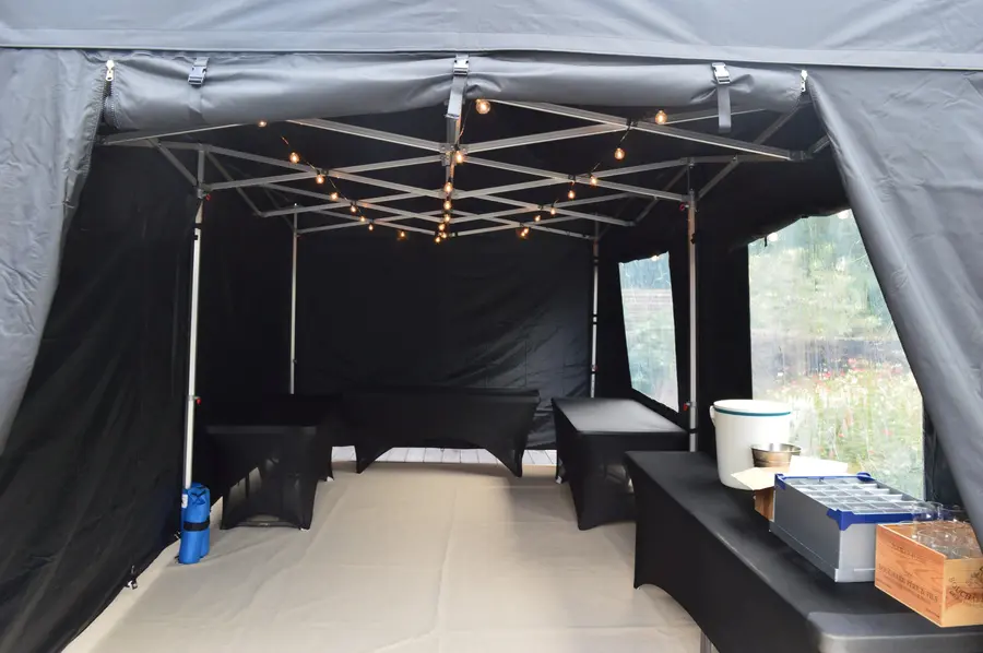 Inside a black gazebo set up as a bar with festoon lighting