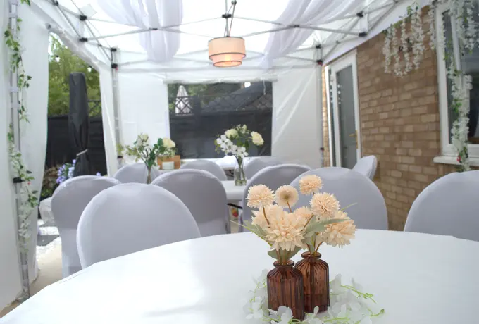 A table laid for a garden party under one of our gazebos: white cloth, chair covers and flowers